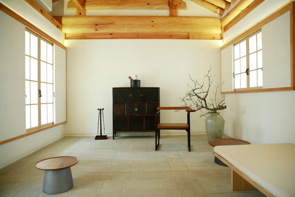 A serene Japanese-inspired room with minimalist furniture and natural wooden beams.