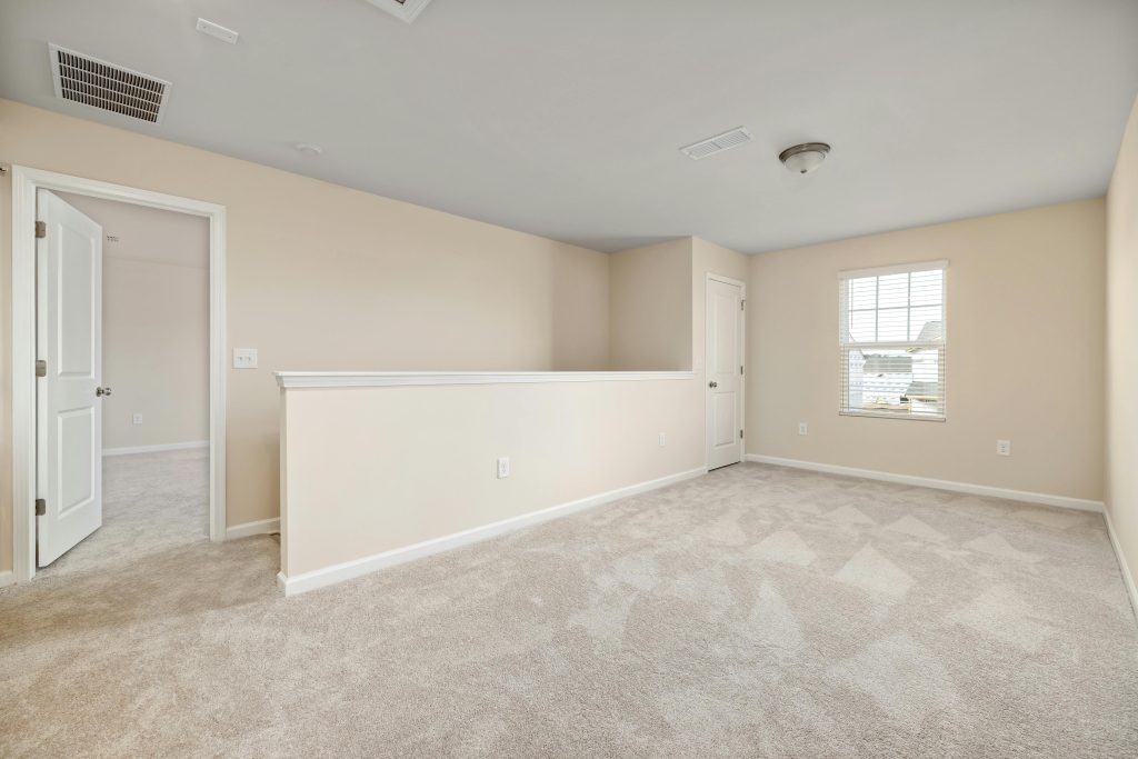 A bright, empty room with beige walls and carpet, ready for interior design ideas.