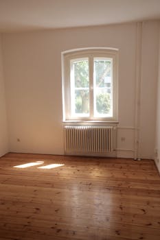 Spacious empty room with wooden floor and large window in Berlin, ideal for interior planning.