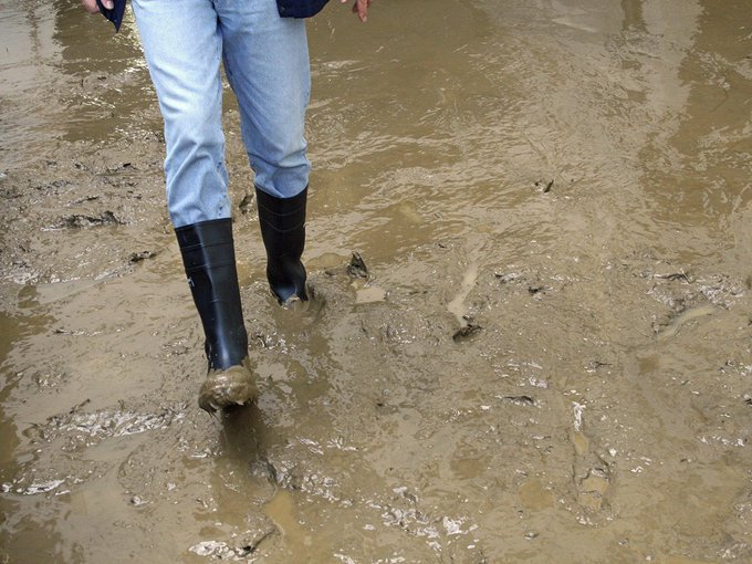 person wearing protective gloves and boots during flood damage cleanup in UK property